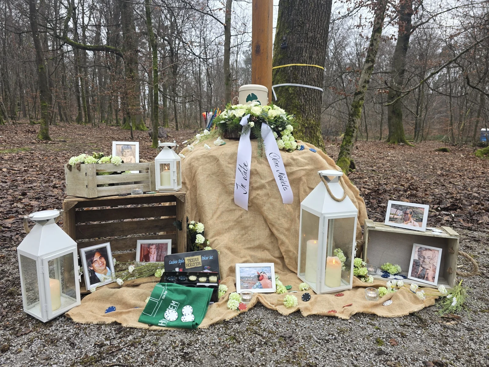 Abschiedsplatz im Wald mit Blumen, Laternen und Erinnerungsbildern